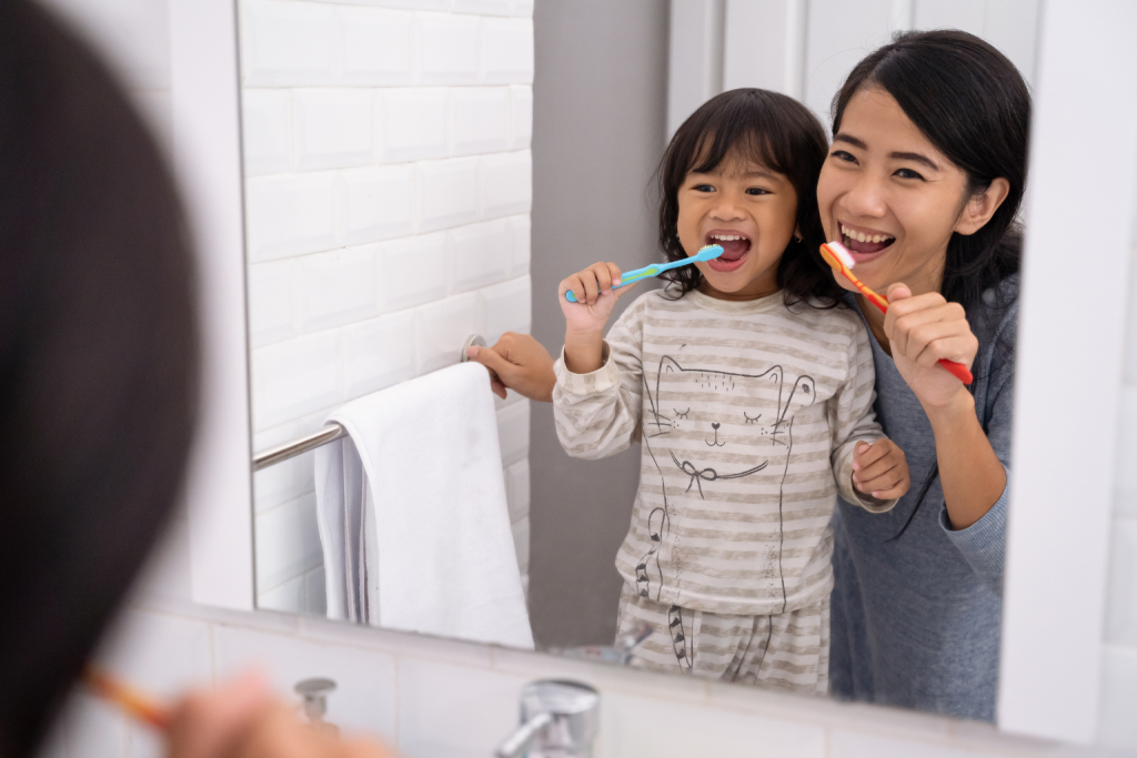 Mother and daughter brushing teeth together to model a consistent bedtime routine and encourage healthy nighttime habits for kids.