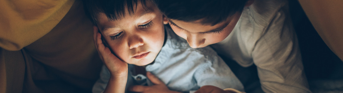 Siblings reading bedtime stories to before sleep.